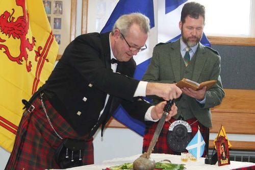 Lanark, Frontenac, Lennox & Addington MPP Randy Hillier carves the beast while his federal counterpart, Scott Reid, reads Robbie Burns’ Address to a Haggis. Photo/Craig Bakay